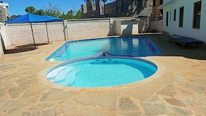 Une piscine avec une plage en pierre et un bordure bleue.