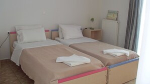Ett hotellrum med två sängar, ett element och ett fönster med gardiner.
