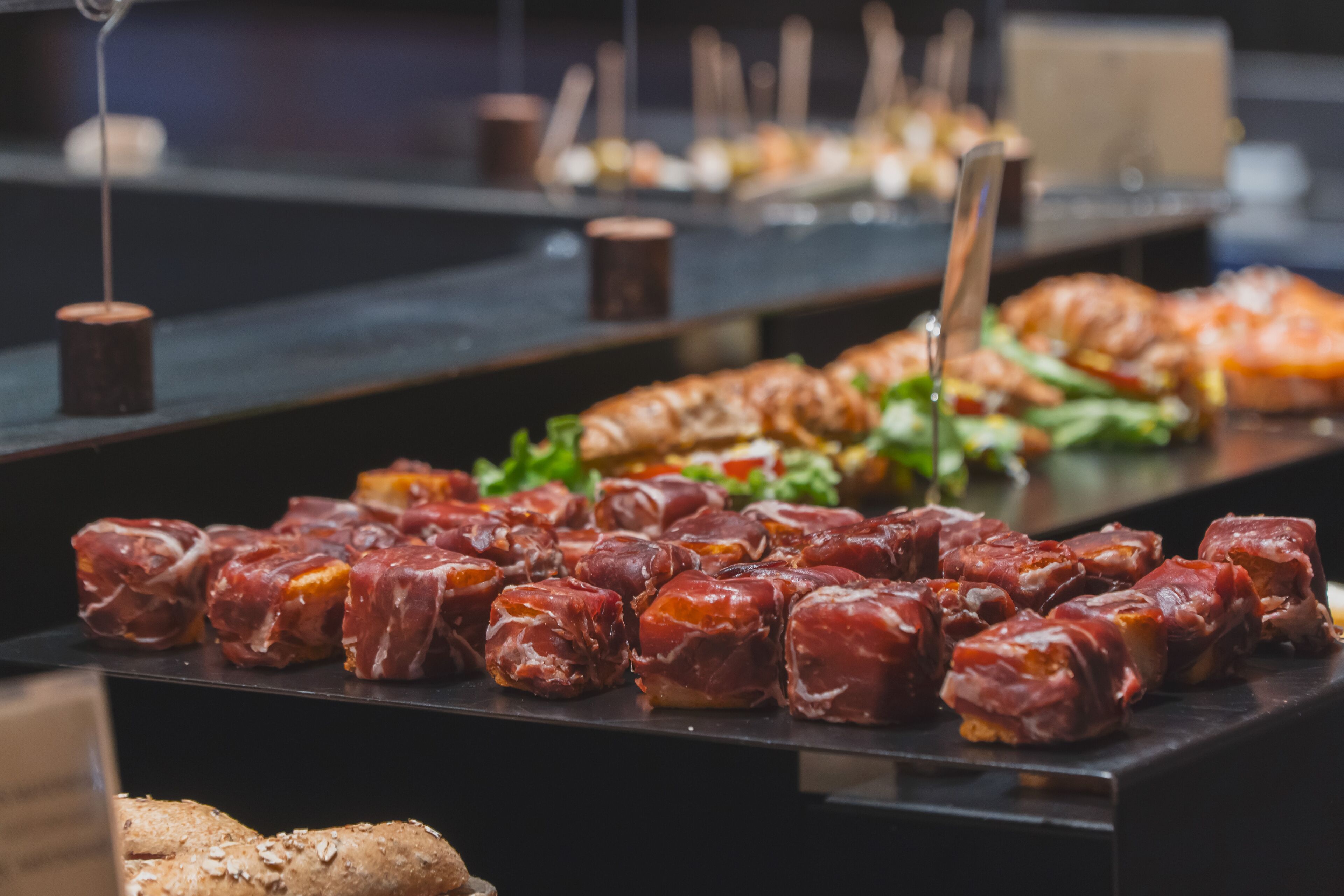 Una mesa de buffet con diversos alimentos, incluyendo pasteles y carnes.