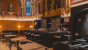 A bar area with a counter, stools, and a seating area with tables and chairs. - Hotel Zenit Convento San Martín (San Sebastián)
