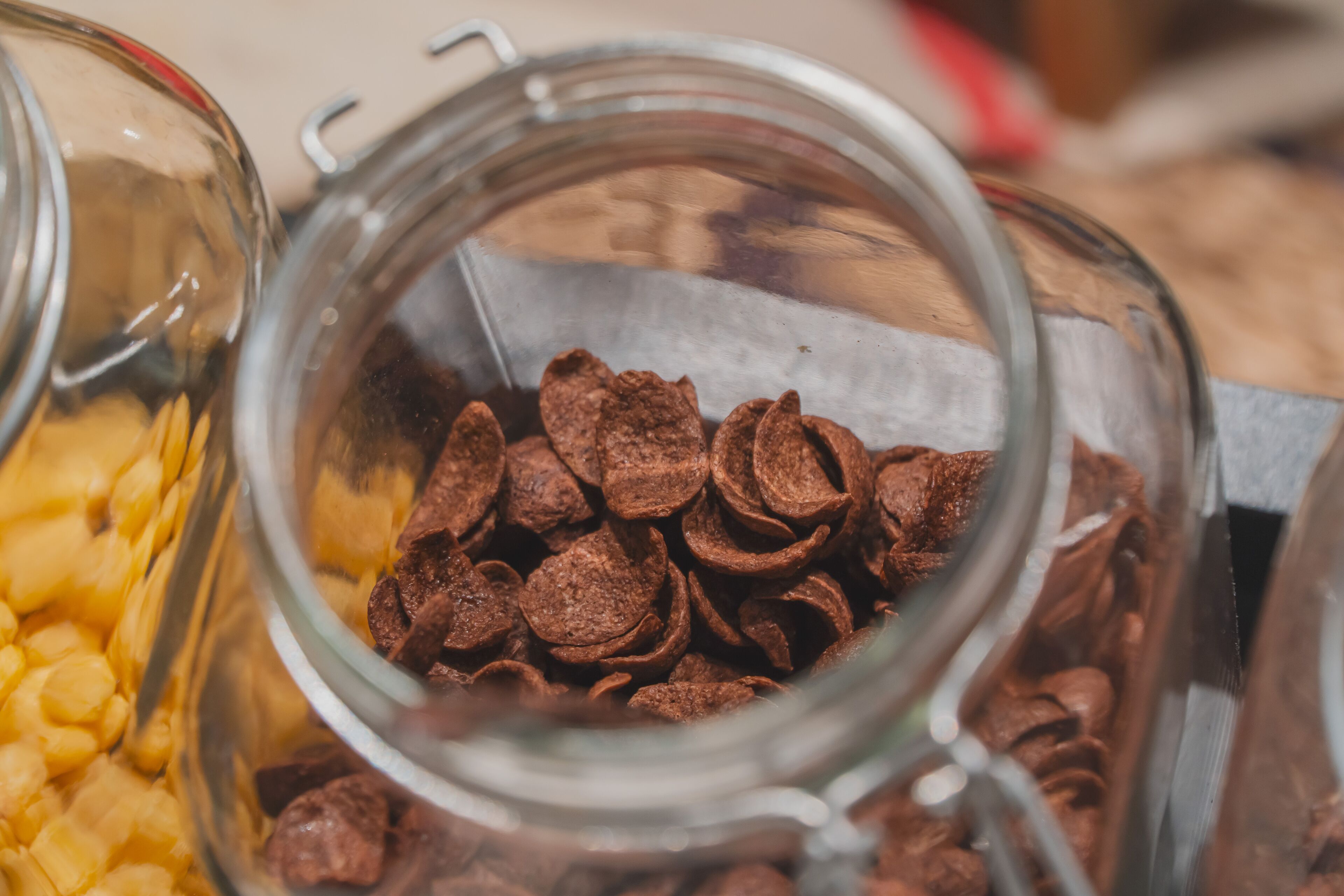 A glass jar filled with chocolate chips and a container of yellow cereal flakes.