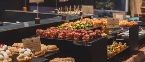 A buffet with various food items including pastries, sandwiches, and salads.