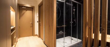 A modern bathroom with a wooden floor, a glass shower enclosure, and a wooden partition.