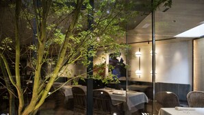 An indoor dining area with glass walls, a tree, and a table with chairs. - Hotel Zenit Convento San Martín (San Sebastián)