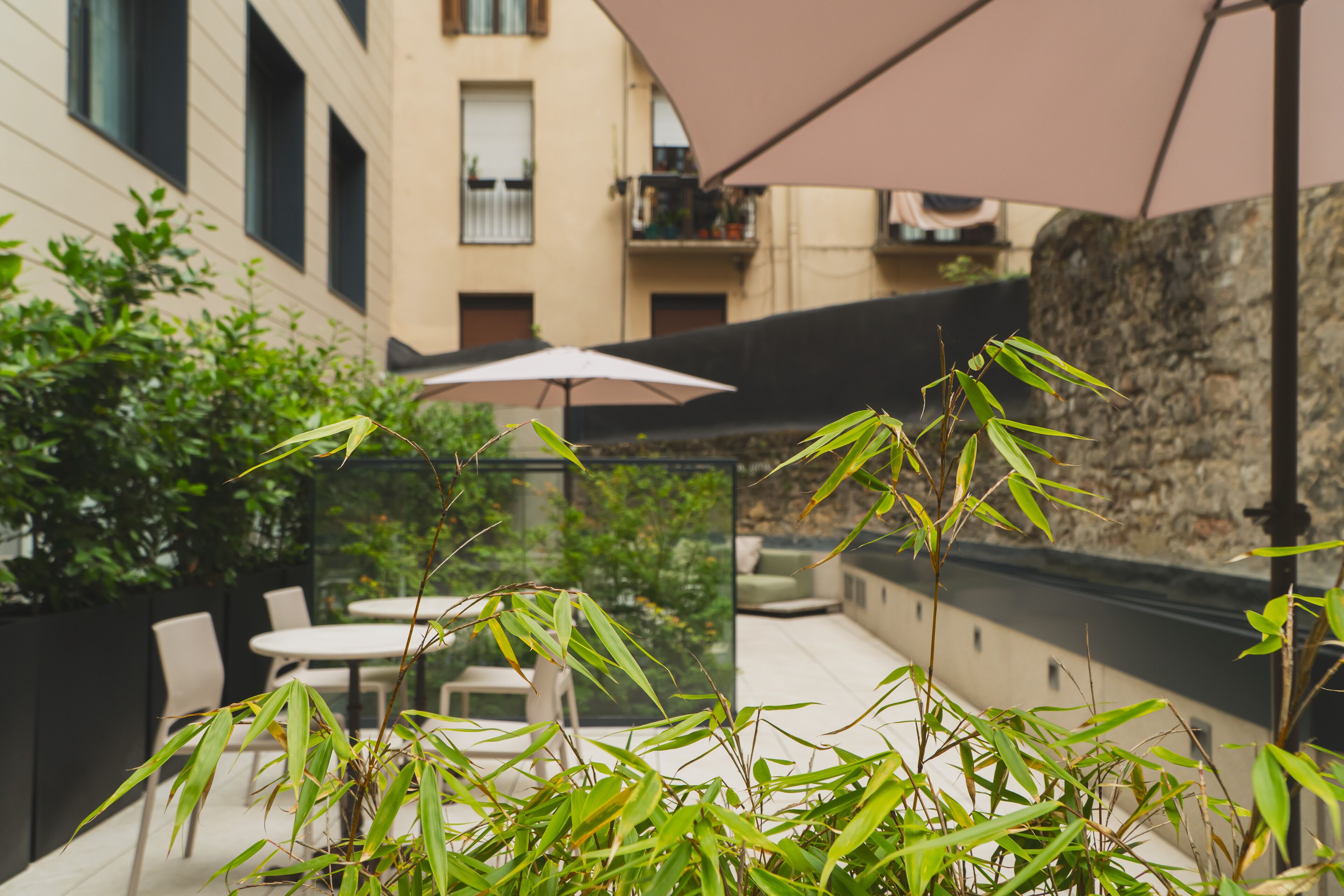 Patio esterno con tavolo e sedie, immerso nel verde e delimitato da un muro in pietra.