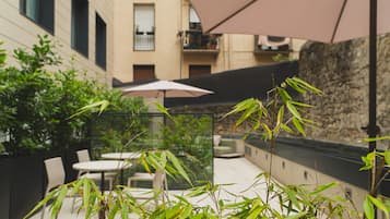 Patio esterno con tavolo e sedie, immerso nel verde e delimitato da un muro in pietra.