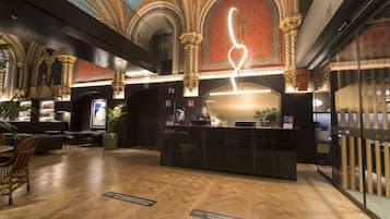 A hotel reception area with a modern design, featuring a reception desk, seating area, and a decorative ceiling.