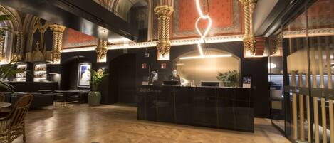 Ein Hotel-Empfangsbereich im modernen Design mit einer Rezeption, einer Sitzecke und einer dekorativen Decke.