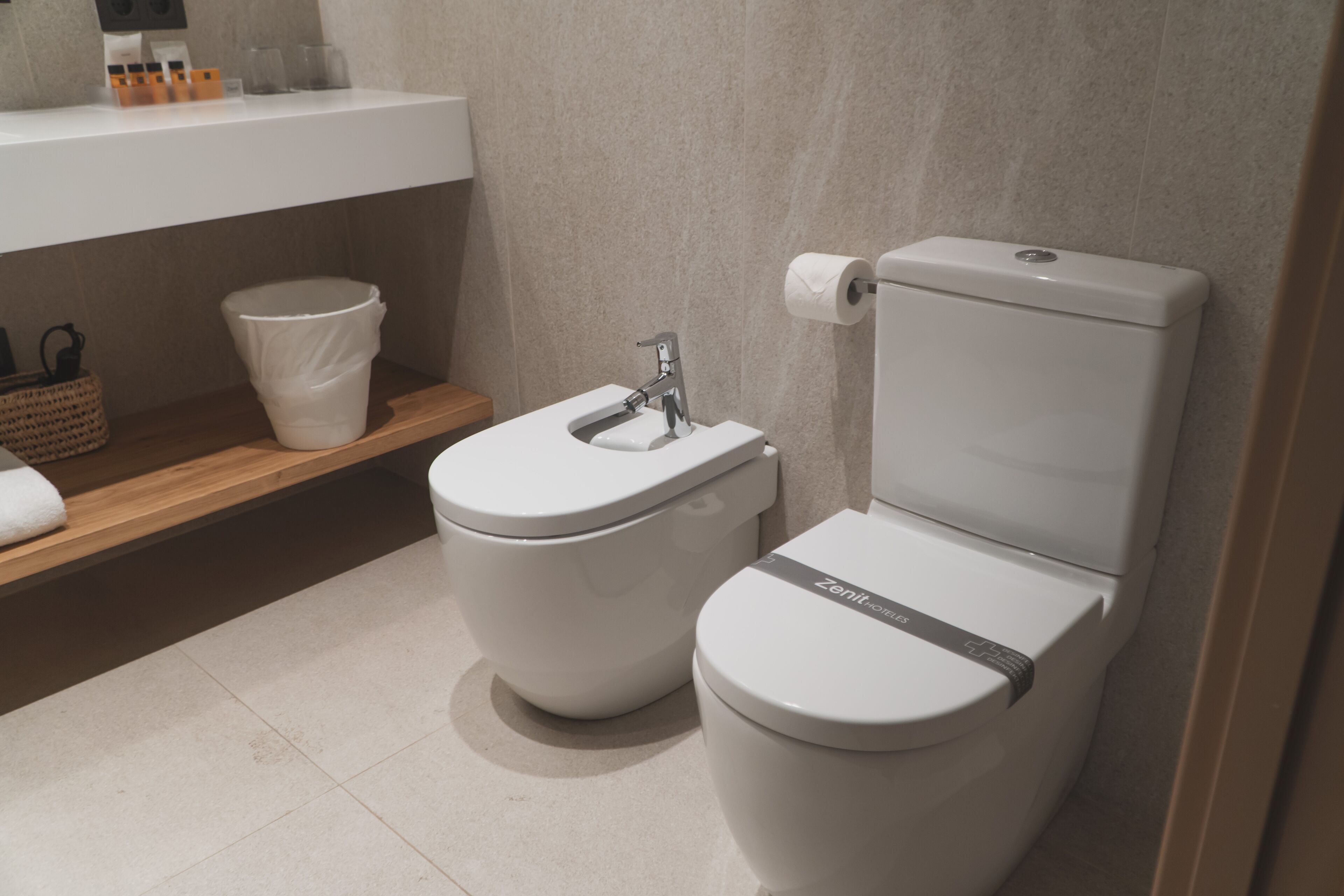 A modern bathroom with a white toilet, a sink, and a shelf with toiletries.