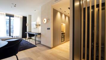A modern hotel room with a dining area, a kitchen, and a staircase.