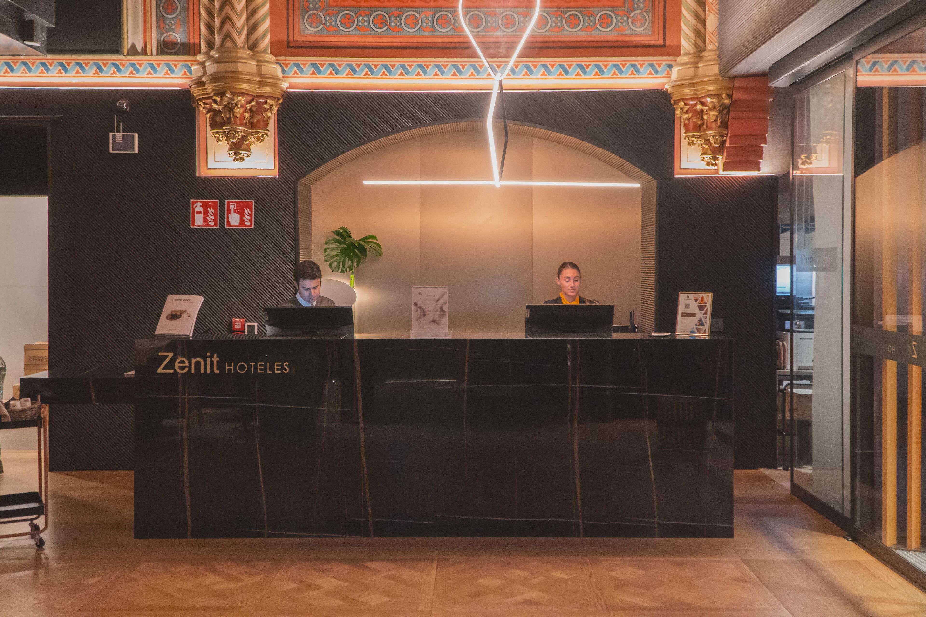 A reception desk with a sign reading "Zenit Hotels".