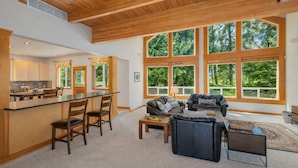 A spacious living area with a large window, a kitchen with a bar, and a cozy seating area.