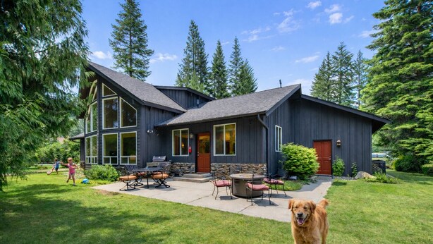 A modern house with a large patio, a stone fireplace, and a well-maintained lawn.
