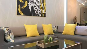 A modern living room with a grey sofa, yellow cushions, a cactus centerpiece, and a zebra-striped artwork on the wall.