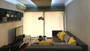 A modern living room with a sofa, TV, and a small table with decorative items. - Metro Court Apartments (Limassol)