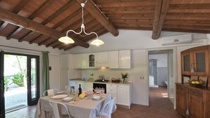 Une cuisine spacieuse avec des meubles blancs, un coin repas avec une table dressée pour quatre personnes et un plafond en bois.