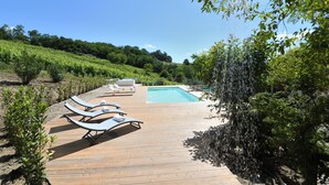 Une terrasse en bois avec des chaises longues et une piscine.