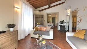 Un salon avec un plafond en bois, un canapé, une table basse et, au fond, un coin repas.