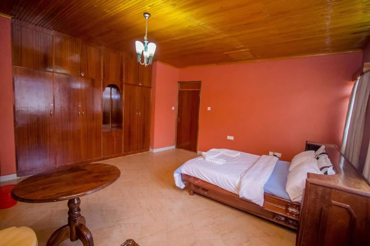 A bedroom with a wooden bed, a wooden wardrobe, and a wooden table.