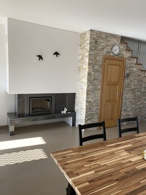 Una sala moderna con una mesa de comedor de madera, una pared de acento de piedra y una chimenea.