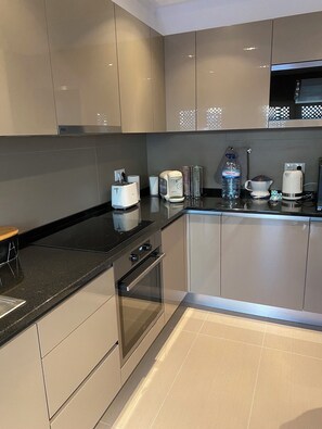 Fully equipped kitchen with sleek cabinetry, black countertop, and essential appliances.