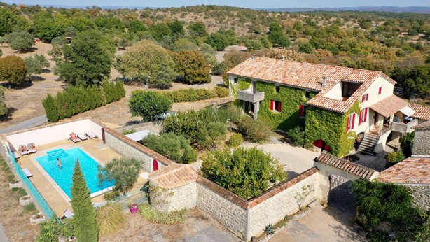 Een villa met zwembad, omgeven door groen en heuvels.