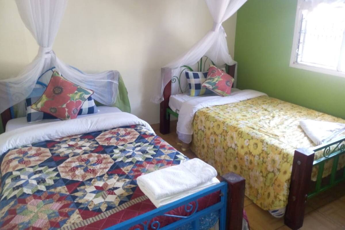 Una habitación con dos camas, cada una con dosel, y un ventanal con vistas.