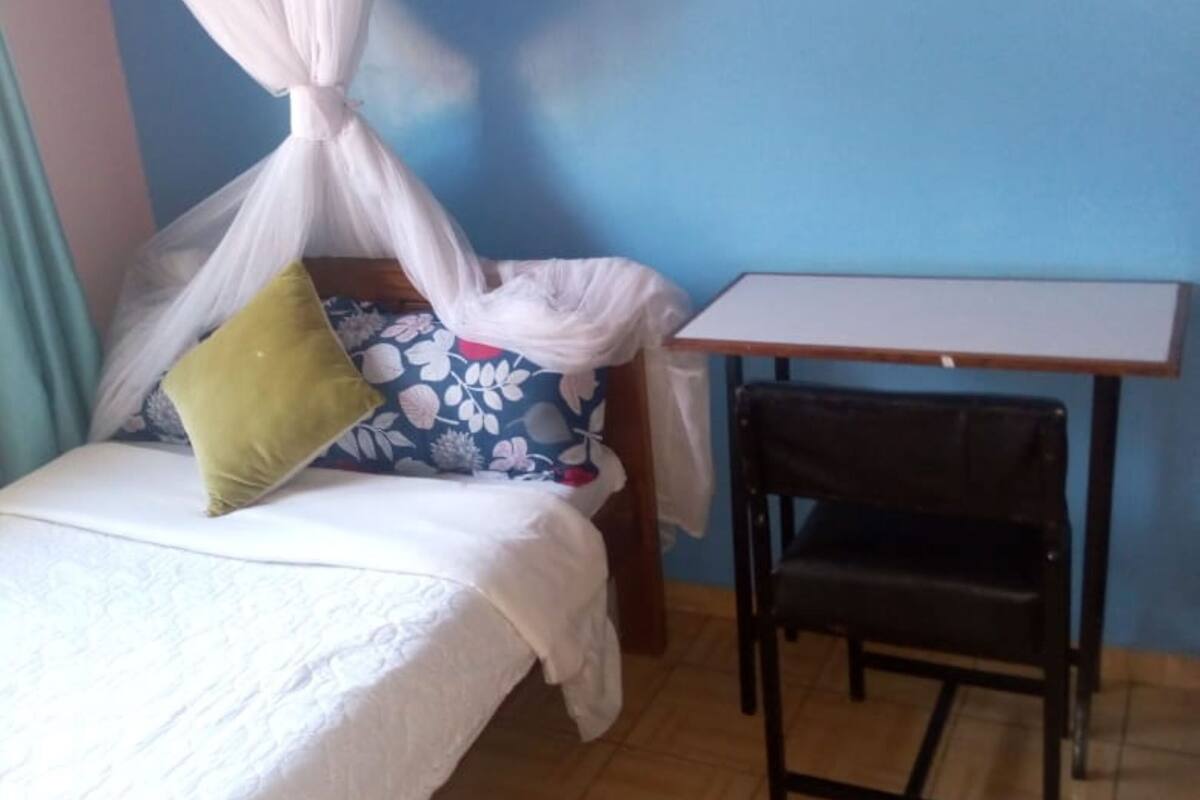Una habitación pequeña con una cama, una silla y un escritorio.
