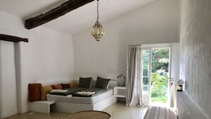 A modern living room with a sectional sofa, a round coffee table, and a view of the outdoors through a large window. - Ferme le Pavillon (Bargemon)