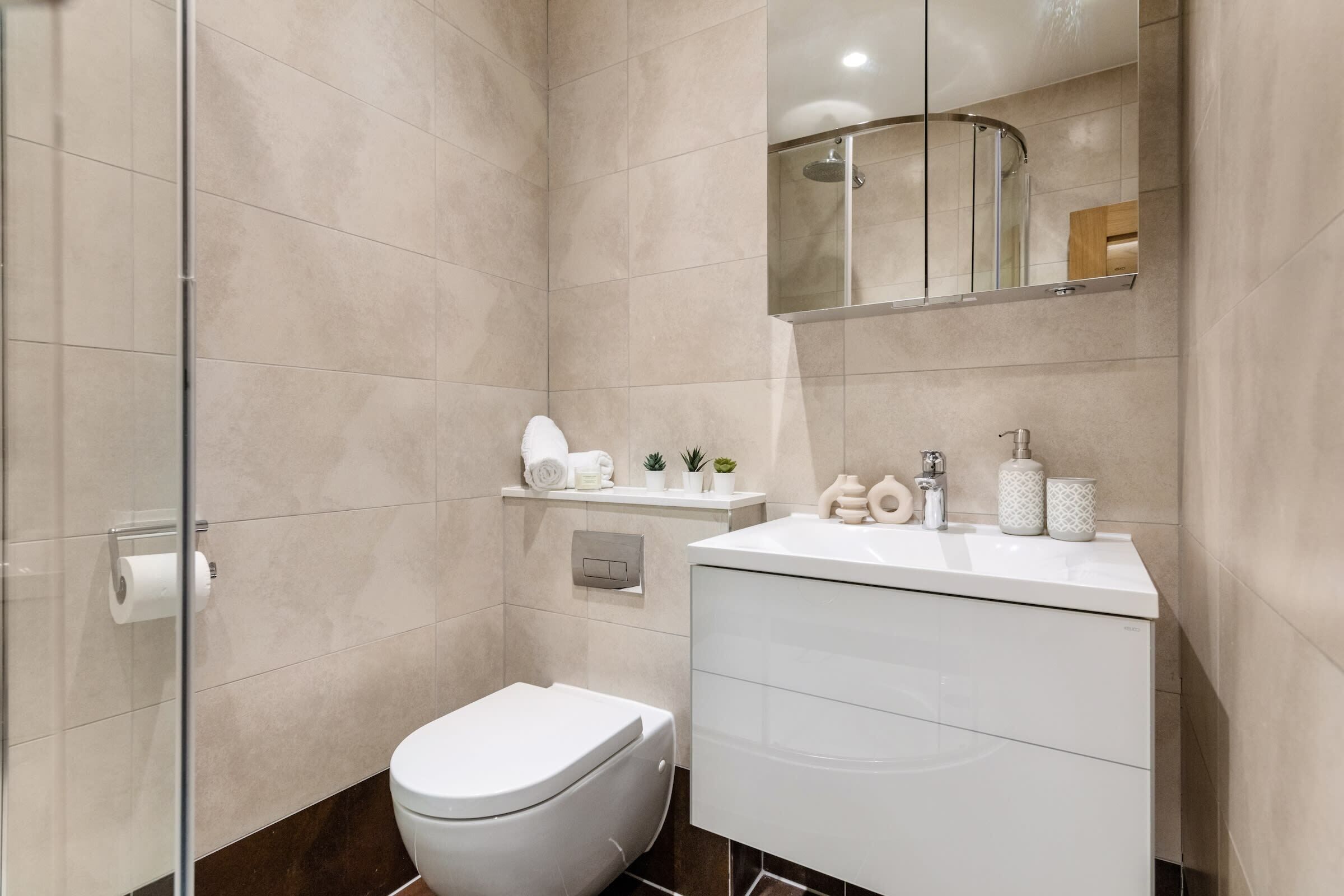 Een moderne badkamer met toilet, wastafel en douche.