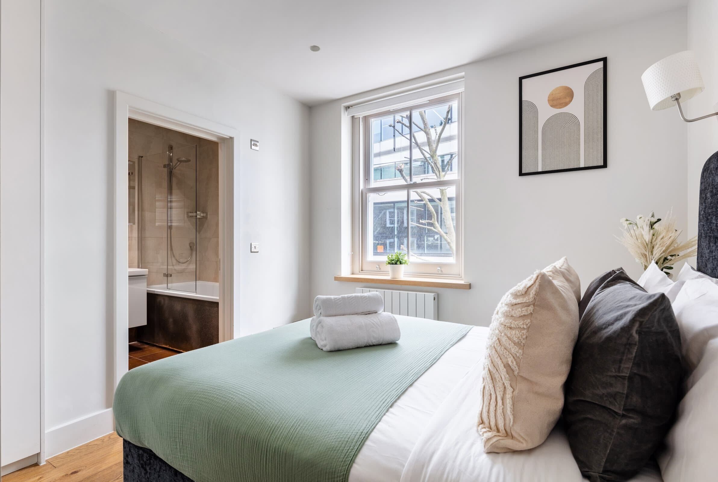Ein modernes Schlafzimmer mit einem großen Bett, einem begehbaren Kleiderschrank, einer Dusche und einem Fenster mit Blick auf die Stadt.