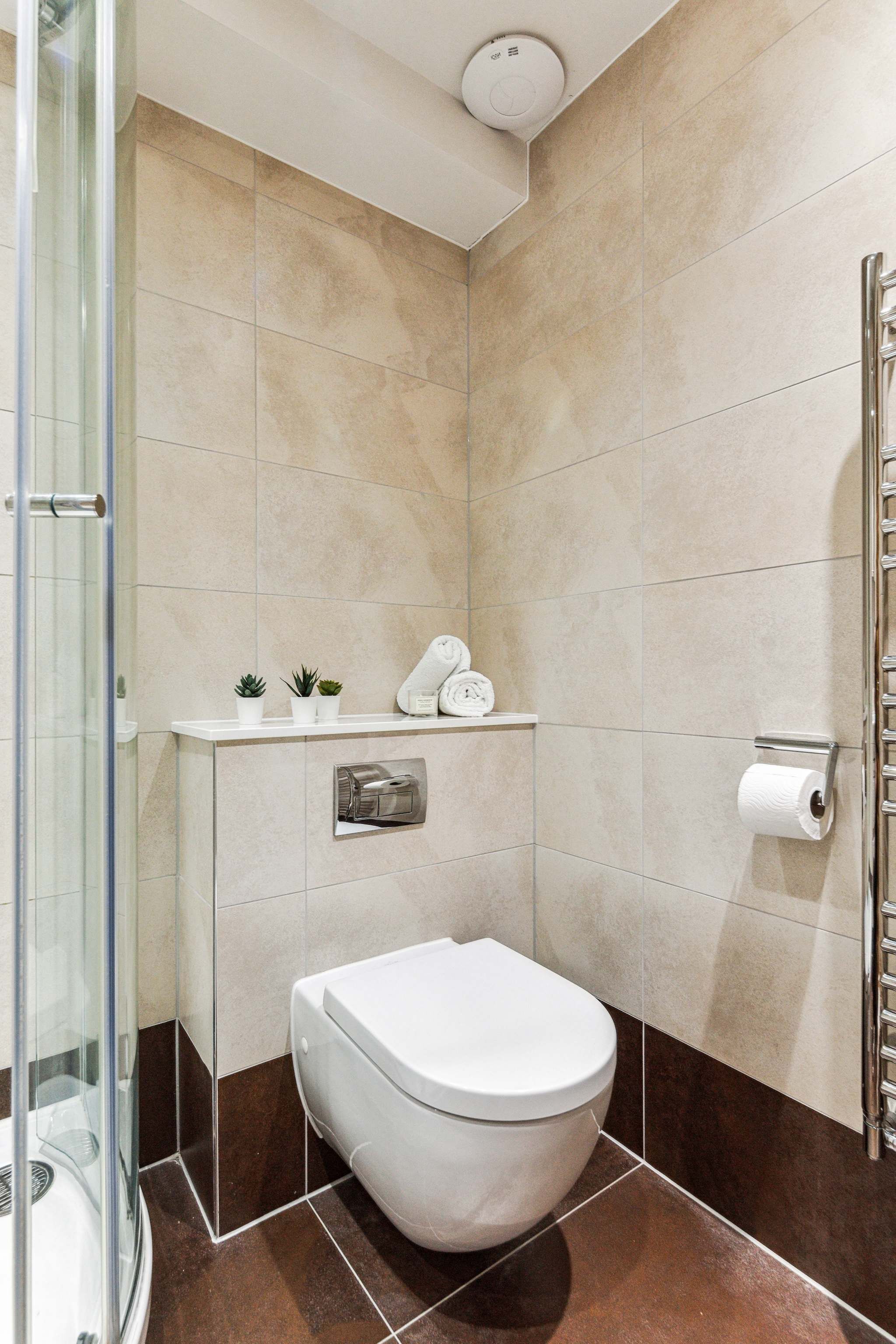 Un bagno moderno con il water, una cabina doccia in vetro e un porta asciugamani.