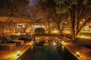 Una piscina al aire libre, sombrillas, sillones reclinables de piscina