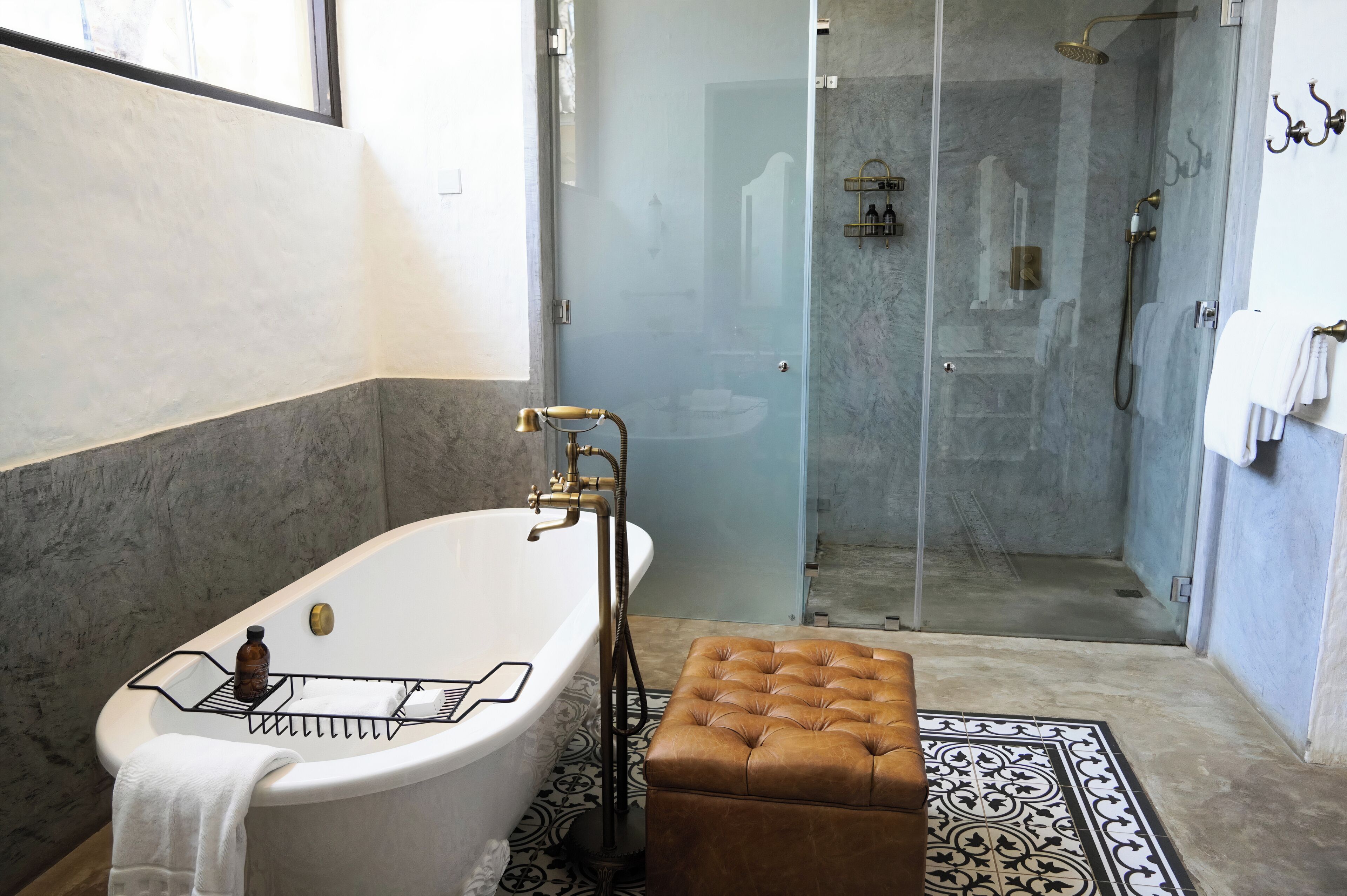 Un baño con una bañera independiente, ducha con cerramiento de vidrio y suelo estampado.