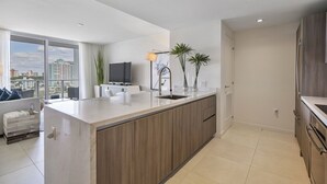 Una cocina moderna con una isla grande, un comedor con sofá y vistas a la ciudad a través de amplias ventanas.