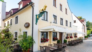 Een hotel met terras, een leeuw decoratie en bloembakken.