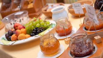 En buffetbod med forskellige spisemuligheder, herunder frugt, marmelade og honning.