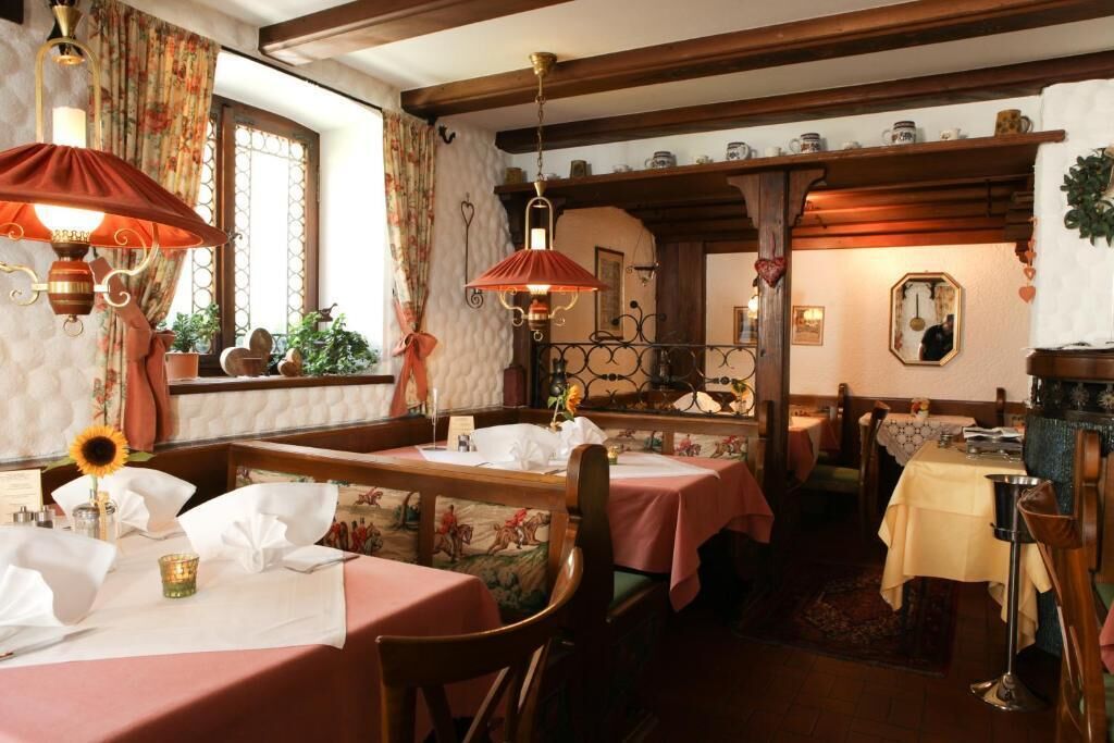 Un restaurante acogedor con vigas de madera, papel tapiz floral y mesas dispuestas para comer.