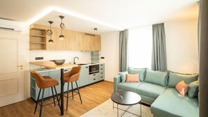 Een modern appartement met een keuken, een eethoek met barstoelen, een woonkamer met een bank en een kleine ronde tafel.