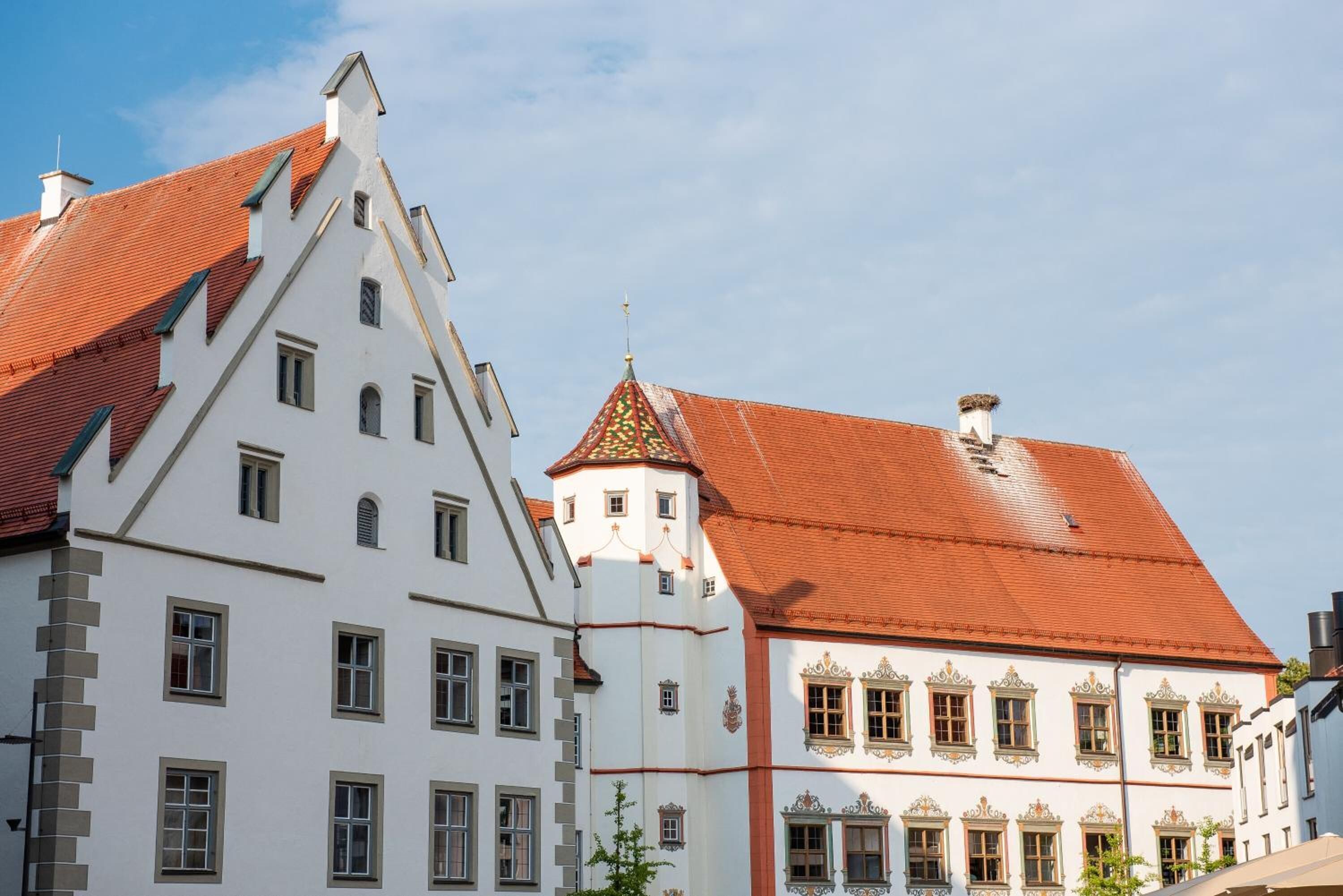 A traditional European building with a steeply pitched roof, a tower with a colorful spire, and a symmetrical facade with evenly spaced windows.