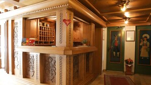 Een houten receptiebalie met een hartvormige decoratie, een boekenkast en ingelijste foto's aan de muur.