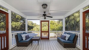 A covered porch with two wicker sofas, a table, and a ceiling fan. - Stay @ Here Comes the Sun on Isle of Palms (Isle of Palms)