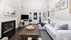 A living room with a fireplace, a sofa, a coffee table, and framed artwork on the walls. - Stay @ Here Comes the Sun on Isle of Palms (Isle of Palms)