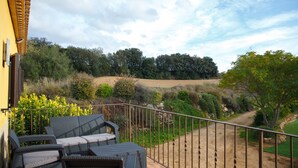 A balcony with wicker furniture and a view of a hilly landscape. - House with private pool, isolated and very quiet at the end of town. (Llampaies)