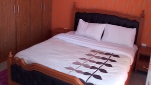 Une chambre à coucher avec un lit, une armoire en bois et un luminaire suspendu.