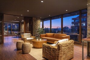A modern living room with a large window, wicker furniture, and a stone accent wall. - The Place  (Santiago)