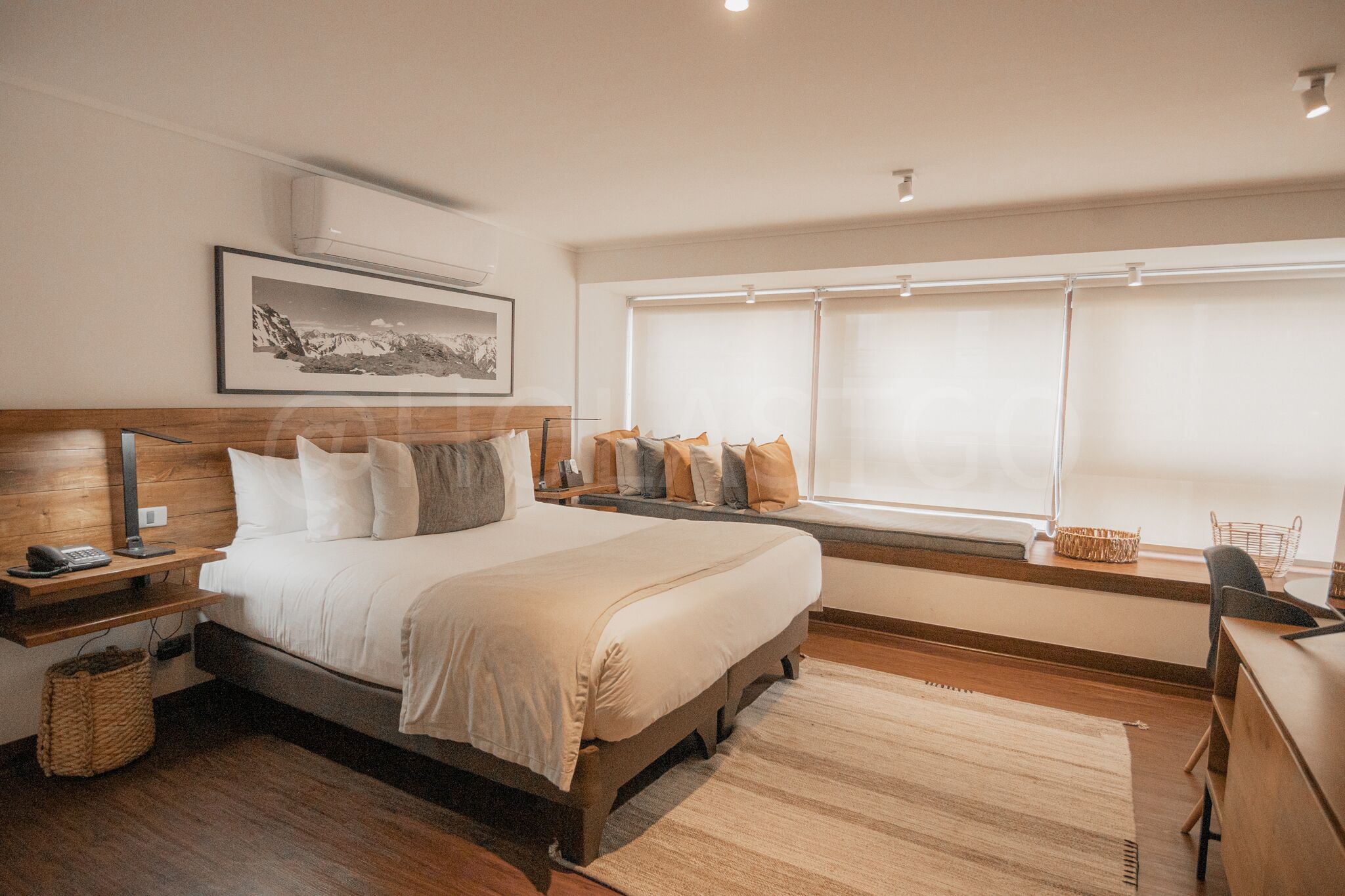 Un dormitorio con cama, mesita de noche, lámpara y una ventana con persianas.