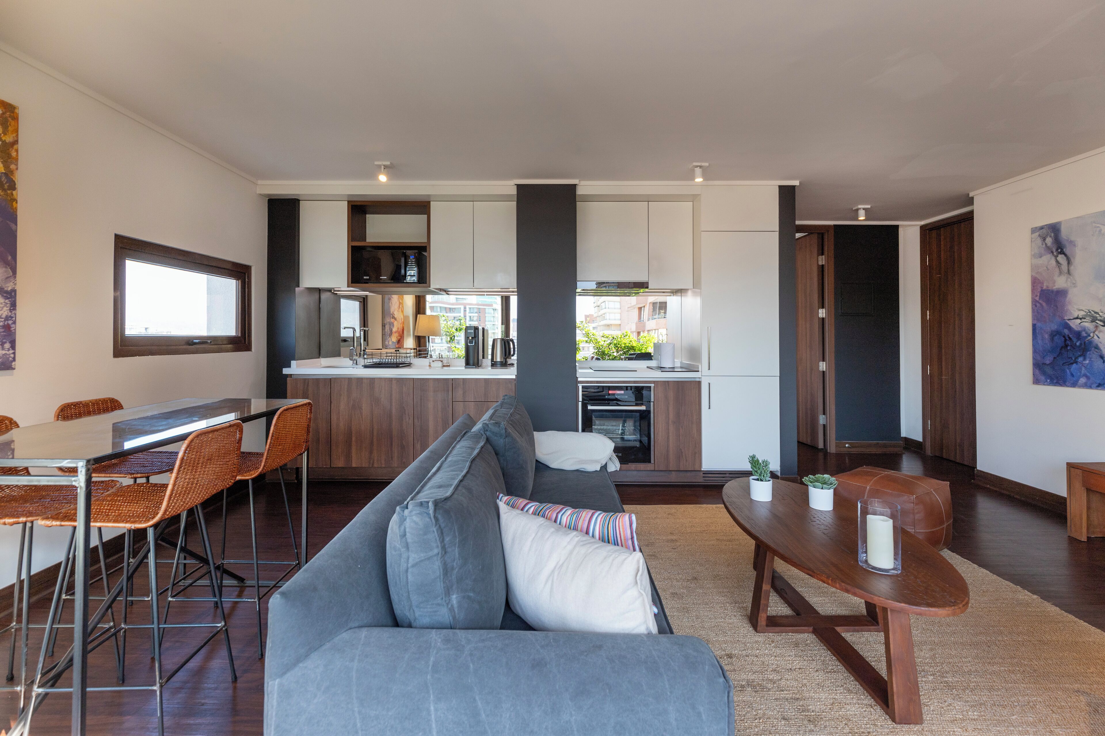 A modern living room with a gray sofa, wooden coffee table, and a dining area with a table and chairs.