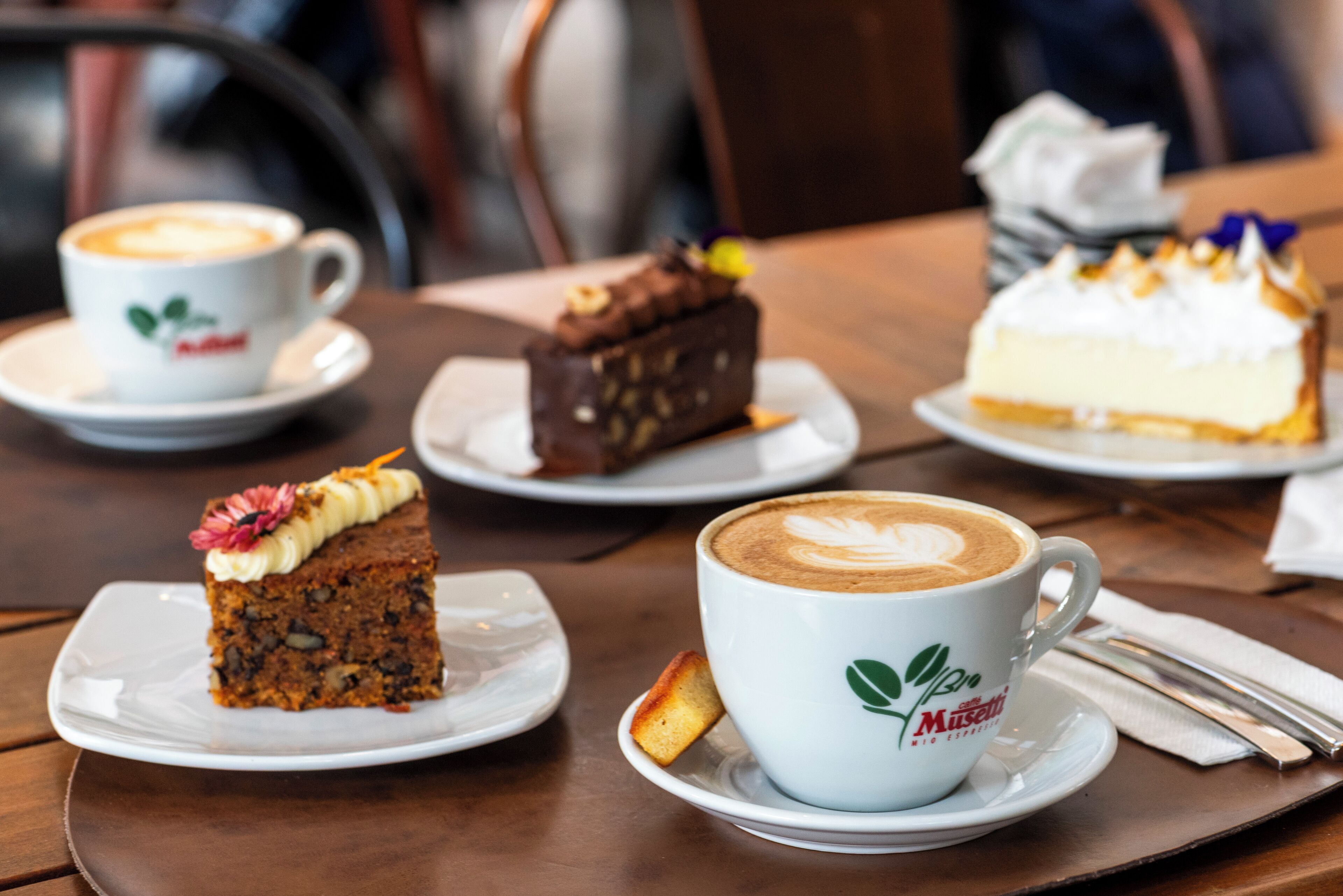 A table with a cup of coffee, a slice of cake, and another slice of cake on a plate.