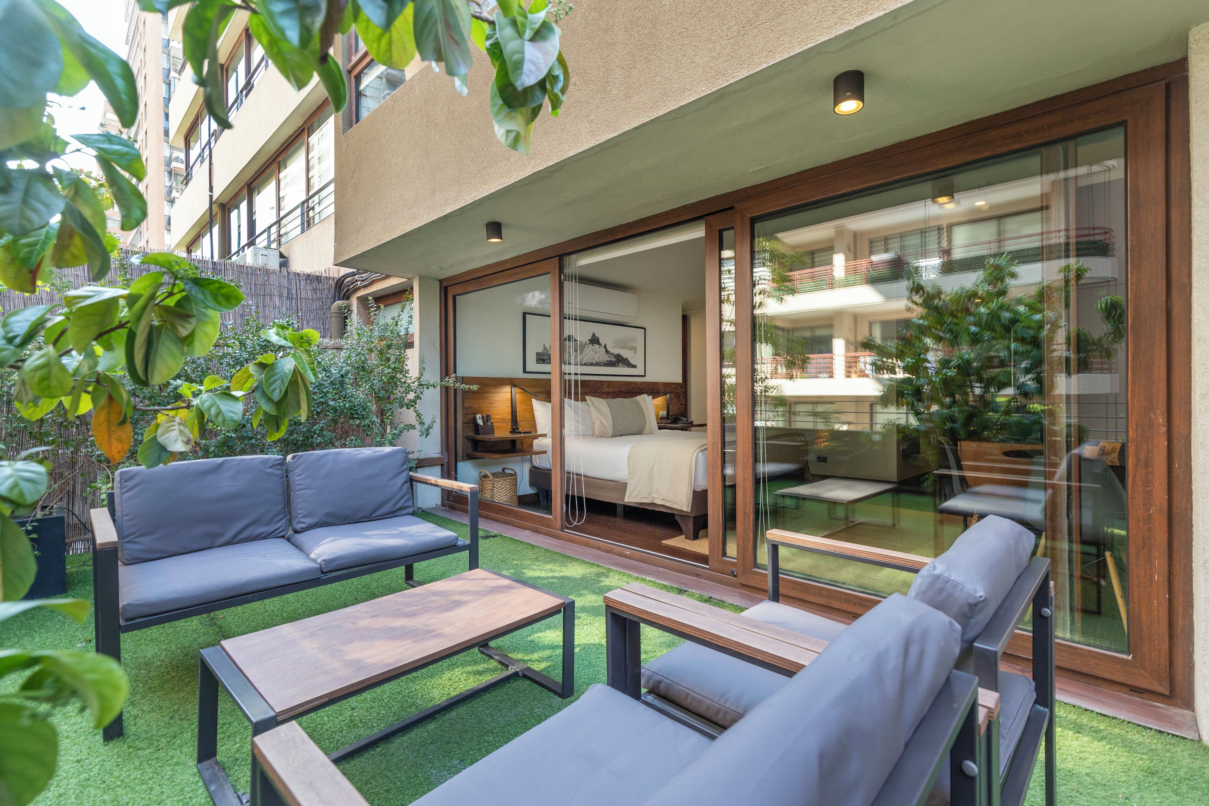 A modern outdoor living area with a sofa, two lounge chairs, and a coffee table.